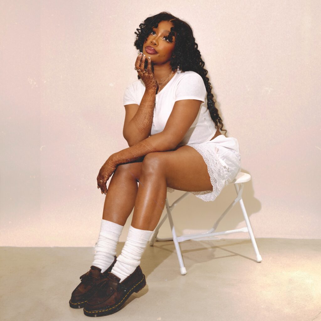 A photo of R&B singer SZA sitting on a chair