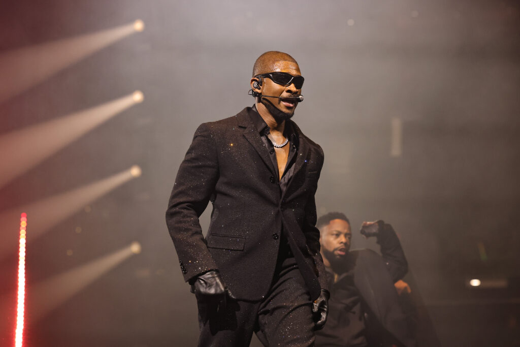 Usher wearing a black suit and shades on his Past Present Future Tour